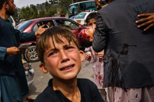 A man carries a bloodied child, as a woman lays wounded on the street after Taliban fighters use guns fire, whips, sticks and sharp objects to maintain crowd control over thousands of Afghans who continue to wait outside the Kabul Airport.
MARCUS YAM / LOS ANGELES TIMES via Getty Images