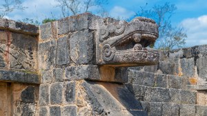Stone sculpture of the feathered snake and god Quetzalcoatl, deity of creation and life for Aztec and Maya civilization, Chichen Itza, Mexico.