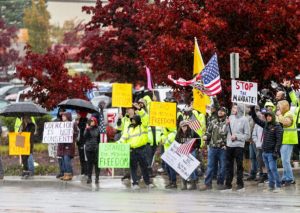 Boeing employees and others wave to passing traffic in the rain as they protest the company’s COVID-19 vaccine mandate, outside the Boeing facility in Everett, Wash., on Oct. 15, 2021. (Lindsey Wasson/Reuters)