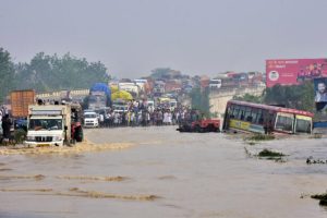 Commuters stand on a flyover on a flooded national highway after river Kosi overflowed following heavy rains near Rampur in India’s Uttar Pradesh state on Oct. 20, 2021. (AFP via Getty Images)
