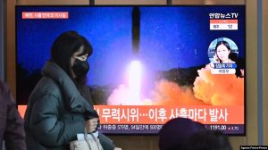 A woman walks past a television screen showing a news broadcast with file footage of a North Korean missile test, at a railway station in Seoul on Jan. 17, 2022.