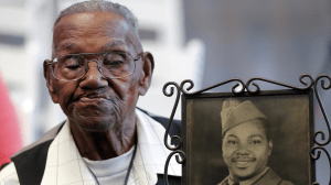 World War II veteran Lawrence Brooks holds a photo of him taken in 1943, when he celebrated his 110th birthday at the National World War II Museum in New Orleans, on Sept. 12, 2019. (AP/Gerald Herbert)