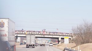 Truckers part of The People's Convoy drive past an overpass with supporters in Okla., on Feb. 27, 2022. (Enrico Trigoso/The Epoch Times)