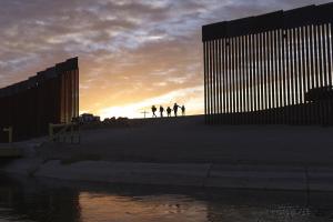 June 10, 2021: A pair of migrant families from Brazil pass through a gap in the border wall to reach the United States after crossing from Mexico to Yuma, Ariz., to seek asylum.    ((AP Photo/Eugene Garcia, File))