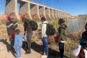 FILE - A Mexican smuggler guides a Haitian family across the Morelos Dam over the Colorado River from Los Algodones, Mexico,   (AP Photo/Elliot Spagat, File)