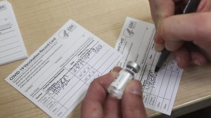 A health care worker fills out a COVID-19 vaccination record card. Photo: Angus Mordant/Bloomberg via Getty Images