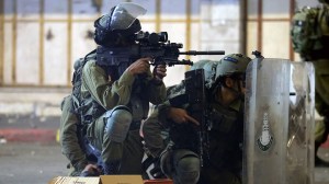 An Israeli soldier aims his weapon while others take cover behind their shields during a Palestinian protest amid a flare-up of Israeli-Palestinian violence, in Hebron in the Israeli-occupied West Bank May 11, 2021.  (REUTERS/Mussa Qawasma)