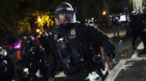 A Portland police officer pushes back protesters, Saturday, Sept. 26, 2020, in Portland. The protests, which began over the killing of George Floyd, often result frequent clashes between protesters and law enforcement. (AP Photo/John Locher) (AP Photo/John Locher)