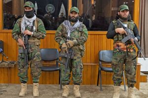 Taliban fighters stand guard at the backstage as the army chief of staff Qari Fasihuddin Fitrat (L), acting defence minister of Afghanistan Mohammad Yaqoob Mujahid (C) and Taliban defence ministry spokesman Enayatullah Khawarizmi speak during a press conference in Kabul on August 28, 2022. (WAKIL KOHSAR/AFP via Getty Images)
