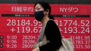 A person wearing a protective mask walks in front of an electronic stock board showing Japan's Nikkei 225 index at a securities firm, Sept. 9, 2022, in Tokyo. (AP Photo/Eugene Hoshiko / AP Newsroom)