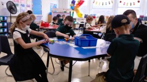 Masked students work in a classroom. ( Allison Dinner/Bloomberg via Getty Images)