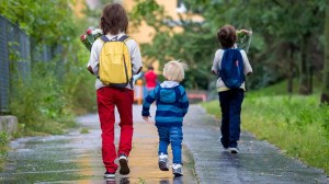Happy school children, holding bouquet of flowers, going to school first day, rainy autumn day in September (istock )