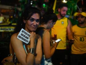 A supporter of Brazilian President and re-election candidate Jair Bolsonaro holds a sign reading, “What kind of person wants a thief for a president???”, a reference to Lula da Silva’s corruption conviction, in Rio de Janeiro, Brazil, on October 30, 2022. (ANDRE BORGES/AFP via Getty Images)
