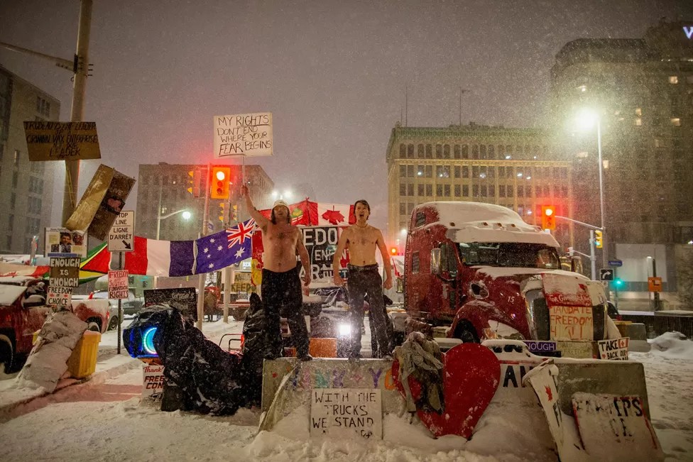 CARLOS OSORIO / REUTERS
Image caption,
People take part in protests against coronavirus vaccine mandates near Canada's parliament in Ottawa. Ontario declared a state of emergency in response to two weeks of the trucker-led protests.
