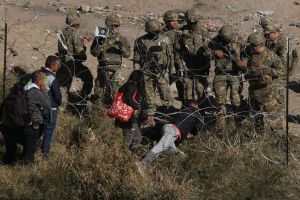Illegal immigrants cross the razor fence placed by elements of the Texas National Guard on the banks of the Rio Grande, in El Paso, Texas, border with Ciudad Juarez, Chihuahua state, Mexico, on Dec. 20, 2022. (Herika Martinez/AFP via Getty Images)