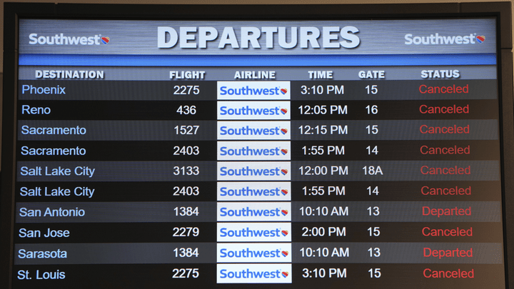 Cancelled Southwest Airlines flights are seen in red on the departures flight schedules at the Southwest terminal at the Los Angeles International Airport on Tuesday.  (AP/Damian Dovarganes / AP Newsroom)