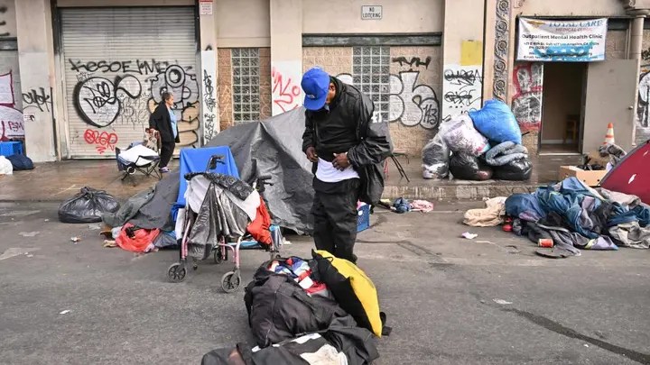 Homeless people stand with their belongings in front of an outpatient mental health clinic in Los Angeles on Dec. 6, 2022. (Photo by FREDERIC J. BROWN/AFP via Getty Images)