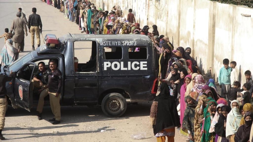 Pakistanis line up for hours to receive subsidized bags of flour in Hyderabad on January 10.
